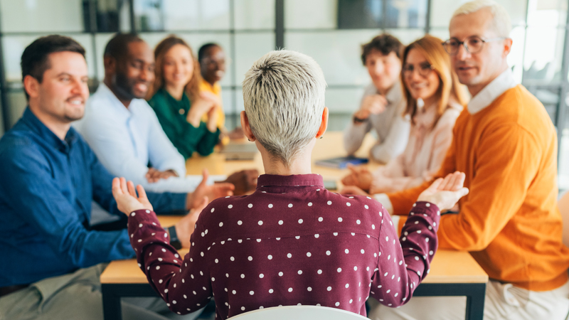 An effective manager speaking to her team and personalizing her language, as they sit around a meeting table