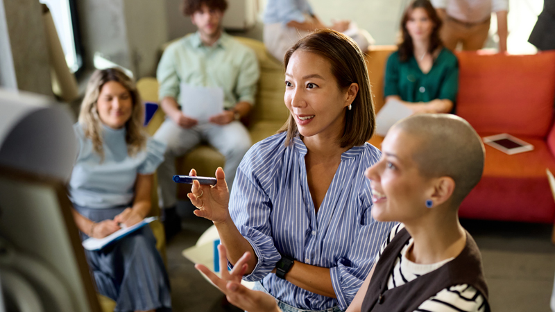 Two female executives leading a decision-making meeting with engaged team members