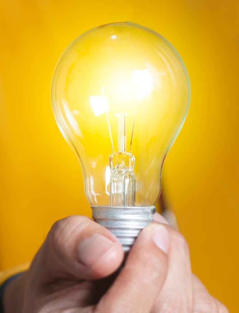 A bright light bulb shining in a man's hand as he experiences an MCode assessment light bulb moment